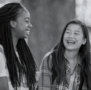 Two people sitting and laughing together outdoors.