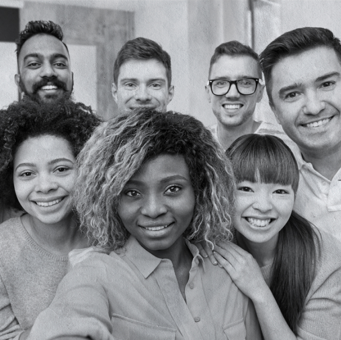 A group of seven people smiling and taking a selfie indoors.